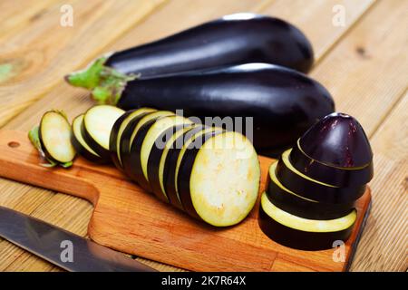 Frische Auberginen in Scheiben geschnitten auf Holztisch in der Küche Stockfoto