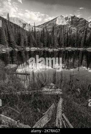Der Ypsilon Mountain und der Mount Chiquita spiegeln sich im ruhigen Wasser des Chipmunk Lake wider, mit dem ersten Licht der goldenen Stunde im Rocky Mountain National Pa Stockfoto