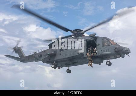 SÜDCHINESISCHES MEER (5. Oktober 2022) Ein der Royal Canadian Navy Halifax-Klasse zugewiesener Seemann HMCS Windipeg (FFH 338) bereitet sich darauf vor, von einem Sikorsky CH-148 Cyclone Hubschrauber auf das Flugdeck an Bord des Arleigh Burke-Klasse Lenkflugkörper-Zerstörers USS Higgins (DDG 76) abgesenkt zu werden Während der Durchführung von multilateralen Operationen im Südchinesischen Meer, Oktober 5. Die Vereinigten Staaten mit der japanischen Maritime Self Defense Force und der Royal Canadian Navy nehmen an mehrseitigen Übungen im Südchinesischen Meer Teil, um die regionale Präsenz der Royal Australian Navy zu unterstützen. Übungen wie diese re Stockfoto