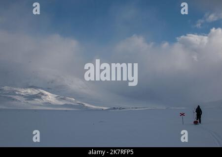 Ein Skifahrer mit Schlitten nähert sich der Alesjaure-Hütte auf dem Kungsleden Trail, Lappland, Schweden Stockfoto