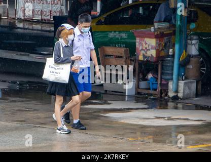 SAMUT PRAKAN, THAILAND, SEP 23 2022, Ein Junge und ein Mädchen in Schuluniformen gehen auf einer nassen Straße Stockfoto