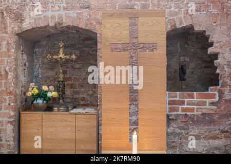 Deutschland, Wismar - 13. Juli 2022: St. Georgen Kirche. Kreuze in Nischen von Ruinen im Gebäude. Einige Blumen und 1 brennende Kerze Stockfoto