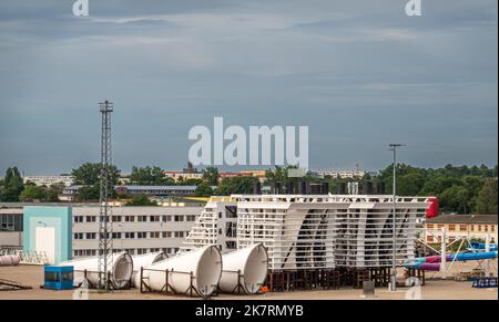 Deutschland, Wismar - 13. Juli 2022: Westhafen-Dock mit großen weißen Schiffbauteilen auf Kai- und Bürogebäuden hinter blauer Wolkenlandschaft Stockfoto