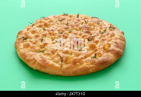 Nahaufnahme mit köstlicher hausgemachter Focaccia auf einem grünen Tisch. Klassische italienische Focaccia aus Sauerteig, Olivenöl und Rosmarinblättern Stockfoto
