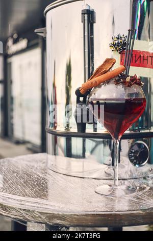 Festlicher Heißgetränk Glühwein für Neujahr und Weihnachten auf der Straße in einem Glas. Vertikales Foto. Stockfoto