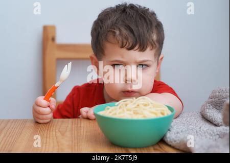 Netter Junge spielt mit seiner Pasta zur Mittagszeit Stockfoto