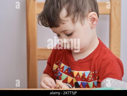 Netter Junge spielt mit seiner Pasta zur Mittagszeit Stockfoto
