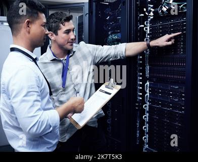 Wenn das WiFi schnell ist, ist es ihnen zu verdanken. Zwei Techniker arbeiten in einem Server-Raum zusammen. Stockfoto