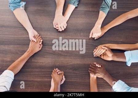 Draufsicht, Hände halten oder psychische Unterstützung bei Gruppentherapietreffen für Psychologie, Vertrauen oder Sicherheit. Männer, Frauen und Diversität Menschen im Gebet Stockfoto