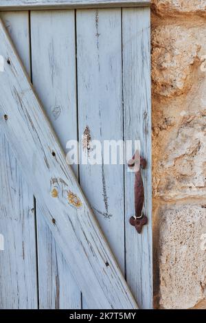 Holzjalousien mit Metallgriff und Steinwand Stockfoto