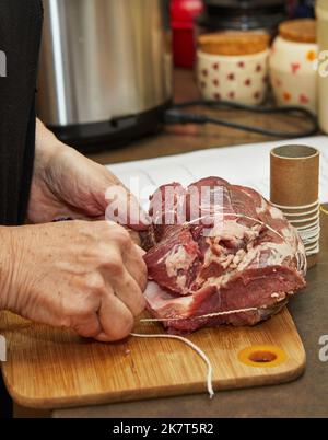 Der Koch bindet das Rindfleisch mit einem Seil und bereitet es für das Backen im Ofen vor Stockfoto