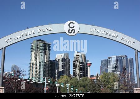 Ein Schild für den Stampede Park mit den Gebäuden im Stadtzentrum im Hintergrund in Calgary, Alberta, Kanada Stockfoto