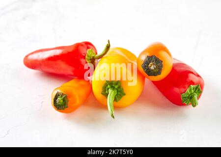 Mini-Paprika auf weißem Marmor, fertig zum Kochen und Essen Stockfoto