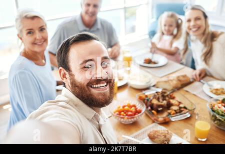 Selfie, Mittagessen und große Familie essen gemeinsam Essen für Feiern, Liebe und Pflege am Esstisch ihres Hauses. Porträt des jungen Mannes mit Stockfoto