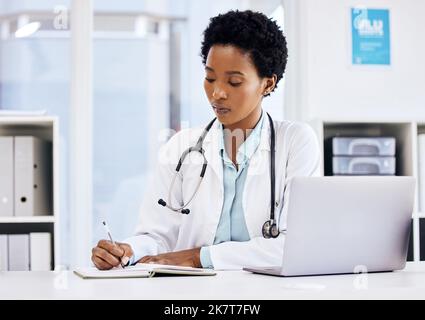 Notizen machen, um ihre Fähigkeiten zu verbessern. Eine attraktive junge Ärztin, die sich Notizen macht, während sie an ihrem Schreibtisch im Büro arbeitet. Stockfoto