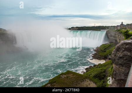 Niagara Horseshoe fällt bei Sonnenuntergang - blaues Wasser, Dunst und wolkiger Himmel. Dramatische Töne Stockfoto