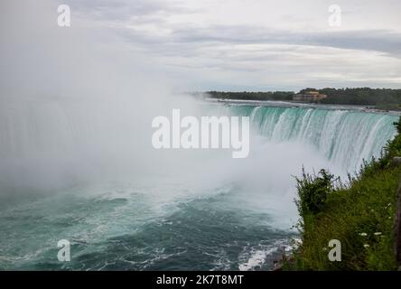 Niagara Horseshoe fällt bei Sonnenuntergang - blaues Wasser, Dunst und wolkiger Himmel. Dramatische Töne Stockfoto