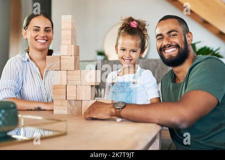 Die Spielzeit macht allen Spaß. Porträt einer glücklichen Familie, die zu Hause mit Holzblöcken spielt. Stockfoto