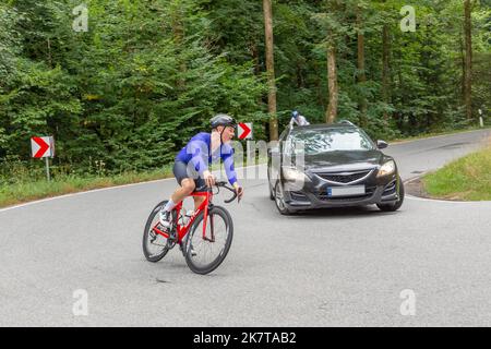 Frankfurt, Deutschland - 25. August 2022: Radrennfahrer des Teams superciao bei einem Orientierungsrennen in Hessen - überholen ein Auto, Deutschland. Stockfoto