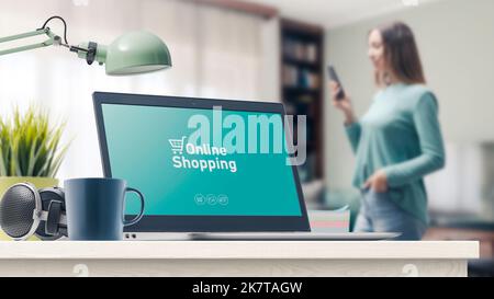 Online-Shopping-Website auf dem Laptop und Frau mit einem Smartphone zu Hause im Hintergrund Stockfoto