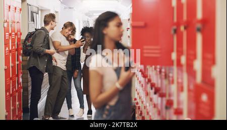 Sei ein Freund, kein Schläger. Ein Mädchen im Teenageralter, das neben ihrem Schließfach steht und in der High School schikaniert wird. Stockfoto