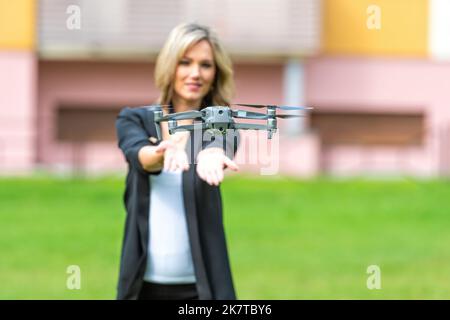 Drohne hebt aus den Händen der jungen blonden Frau, moderne Technologie-Konzept, Fokus auf die Drohne Stockfoto