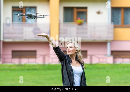 Drohne hebt aus den Händen der jungen blonden Frau, moderne Technologie-Konzept, Fokus auf die Drohne Stockfoto