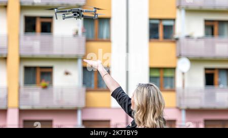 Drohne hebt aus den Händen der jungen blonden Frau, moderne Technologie-Konzept, Fokus auf die Drohne Stockfoto