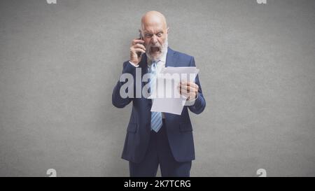 Wütender Kunde, der teure Stromrechnungen hält, ruft beim Energieversorger an und beschwert sich Stockfoto