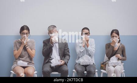 Kranke Menschen mit Erkältung und Grippe sitzen im Warteraum des Krankenhauses und blasen ihre Nase Stockfoto