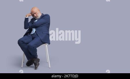 Senior Business Businessman sitzt auf einem Stuhl und schläft Stockfoto