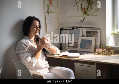 Moderne brünette Geschäftsfrau schreiben Tagebuch Notizbuch Papier Notizen mit Stift auf bequemen Schreibtisch Stockfoto