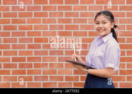 Asiatische Schulmädchen in Uniform stehend Lächeln glücklich Bildung und Lernen mit Platz für Text Stockfoto