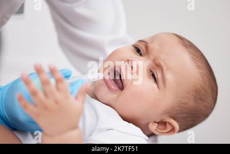 Weint nicht den Kleinen. Ein Arzt, der einem Baby in einem Krankenhaus Medikamente gibt. Stockfoto