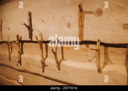 In einem Holzhaus sind handgefertigte Kleiderbügel aus Holz an der Wand befestigt Stockfoto