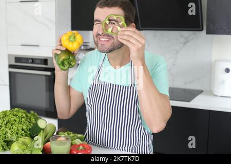 Mann spielt mit grünen Paprika in der Küche Stockfoto