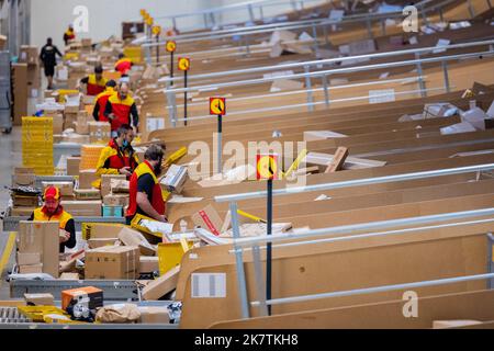 Köln, Deutschland. 19. Oktober 2022. Paketzusteller sortieren und legen Pakete in ihre Zustellfahrzeuge an einer DHL-Zustellbasis der Deutschen Post. Deutsche Post DHL erwartet in der diesjährigen Weihnachtsshopping-Saison erneut Massen von Paketen. Quelle: Rolf Vennenbernd/dpa/Alamy Live News Stockfoto