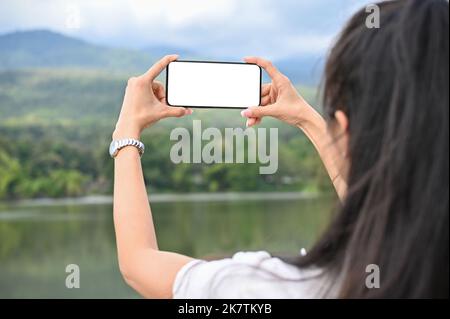 Nahaufnahme, schöne junge asiatische Frau mit ihrem Smartphone, um ein Bild von schönen grünen Berg. Natur-und Lifestyle-Konzept Stockfoto