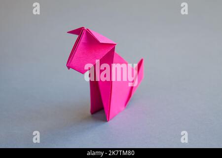 Rosa Papier Hund Origami isoliert auf einem weißen grauen Hintergrund. Stockfoto