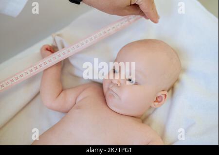 Kinderarzt misst den Körperteil des Babys während der medizinischen Überprüfung Stockfoto