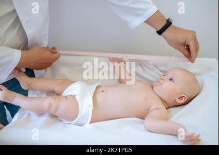 Kinderarzt misst den Körperteil des Babys während der medizinischen Überprüfung Stockfoto