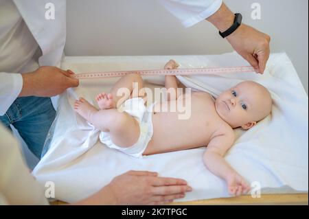 Kinderarzt misst den Körperteil des Babys während der medizinischen Überprüfung Stockfoto