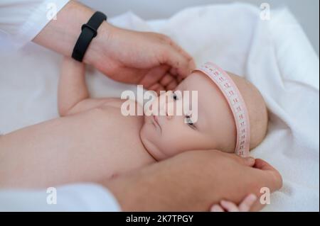 Kinderarzt misst den Körperteil des Babys während der medizinischen Überprüfung Stockfoto