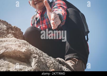 Wandermann, der eine helfende Hand gibt, Hände ausstreckend, um sich gegenseitig zu helfen Stockfoto