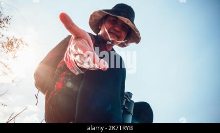 Wandermann, der eine helfende Hand gibt, Hände ausstreckend, um sich gegenseitig zu helfen Stockfoto