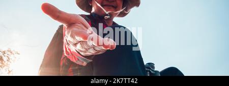 Wandermann, der eine helfende Hand gibt, Hände ausstreckend, um sich gegenseitig zu helfen Stockfoto