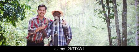 Afrikanischer Trekkingtourist und sein asiatischer Freund halten sich während ihrer Wander- und Abenteuerreise mit Lächeln und Freundschaft an die Hand.Konzept von Freunden und Ave Stockfoto