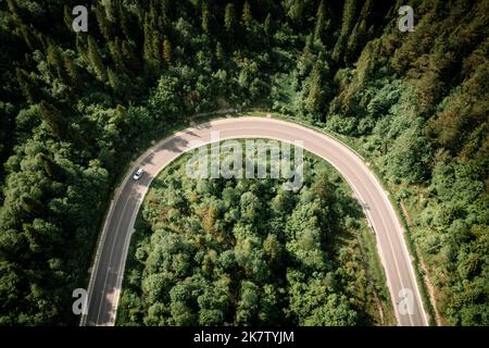 Flug über die Sommerberge mit Bergstraße Serpentin und Wald. Ukraine, Karpaten. Landschaftsfotografie Stockfoto
