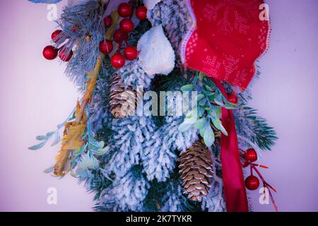 Weihnachtliche Dekoration mit Schnee, Evergreens, Kegelbällen und Feiertagsmotiven. Goldenes und rotes Band. Frohes neues Jahr und frohe Weihnachten. Stockfoto