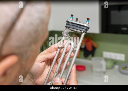 Beschädigtes Heizelement, Waschmaschine in den Händen des Meisters Stockfoto